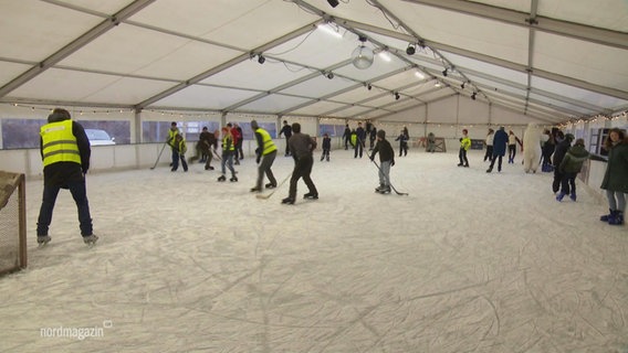 Menschen spielen Eishockey in einer Halle. © Screenshot 