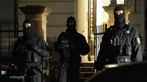 Drei maskierte Polizisten vor einem Gebäude. © Screenshot 