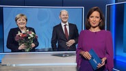 NDR-Moderatorin Romy Hiller vor einem Bild mit Angela Merkel und Olaf Scholz. © Screenshot 