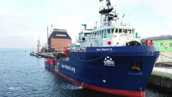 Ein blaues Schiff der Sea Watch liegt im Hafen für seinen Umbau zum Rettungsschiff für Geflüchtete © Screenshot 