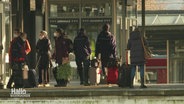 Ein Bahngleis auf dem mehrere Leute mit Taschen und Koffern stehen. © Screenshot 