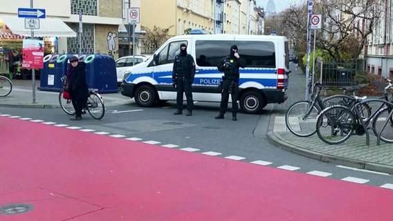 Zwei Mannschaftswagen der Polizei in einer Straße und vor ihr stehen einige Polizisten © Screenshot 