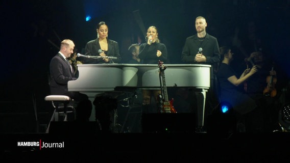 Ein Klavierspieler und Sängerinnen auf einer große Bühne. © Screenshot 