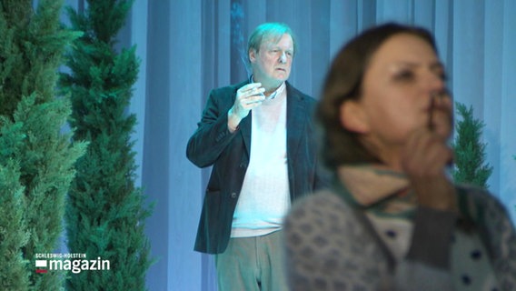 Ein Schauspieler und eine Schauspielerin rauchen auf einer Bühne. © Screenshot 