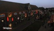 Ein erleuchtetes Gebäude mit nummerierten Türen. © Screenshot 