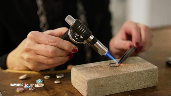 Eine Frau schmiedet einen Ring mit einem Gasbrenner. © Screenshot 
