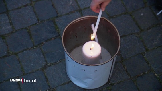 Eine Hand entzündet eine Kerze an der Flamme des Friedenslichts. © Screenshot 
