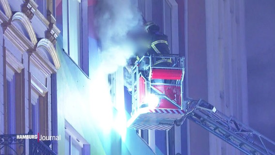 Ein Feuerwehrmann in einem Drehleiter-Korb hilft bei einem Wohnungsbrand an der Hamburger Reeperbahn einem Bewohner. © Screenshot 
