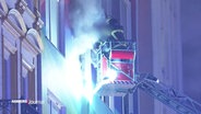 Ein Feuerwehrmann in einem Drehleiter-Korb hilft bei einem Wohnungsbrand an der Hamburger Reeperbahn einem Bewohner. © Screenshot 