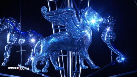 Glitzernde Figuren am Bühnenhimmel: Ein Löwe mit Flügeln, ein Pferd und ein Seepferdchen, überzogen mit Spiegelplättchen. © Screenshot 