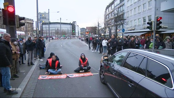 Mitglieder der Klimaorganisation "Letzte Generation" demonstrieren sitzend auf der Straße. © Screenshot 