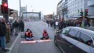 Mitglieder der Klimaorganisation "Letzte Generation" demonstrieren sitzend auf der Straße. © Screenshot 
