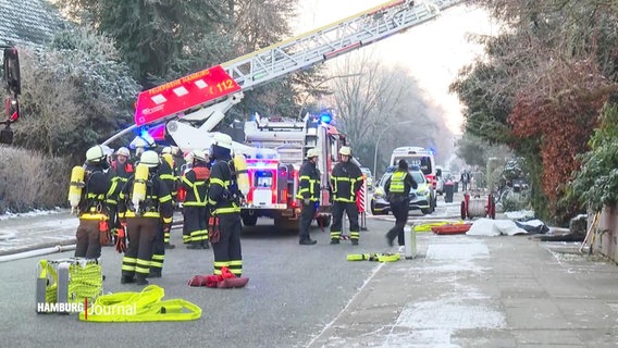 Zahlreiche Feuerwehrkräfte und -Fahrzeuge stehen auf der Straße vor dem betreffenden Haus in Niendorf. © Screenshot 