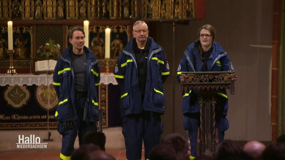 Mitarbeitende des Technischen Hilfswerks sprechen in einer Kirche. © Screenshot 