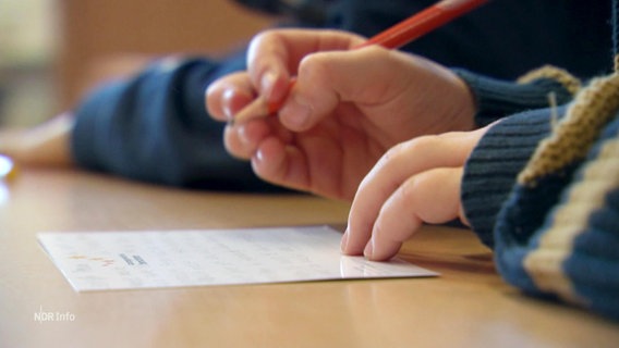 Eine Kinderhand schreibt eine Karte. © Screenshot 