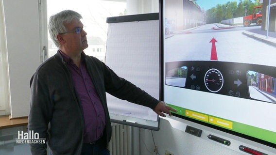 Dieter Quentin vom Fahrlehrerverband zeigt auf eine Fahrsimulation. © Screenshot 