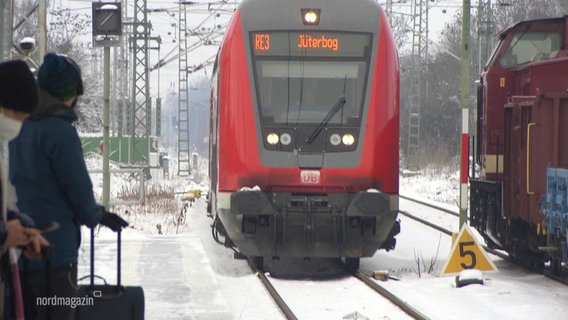 Ein Zug fährt in einen verschneiten Bahnhof. © Screenshot 