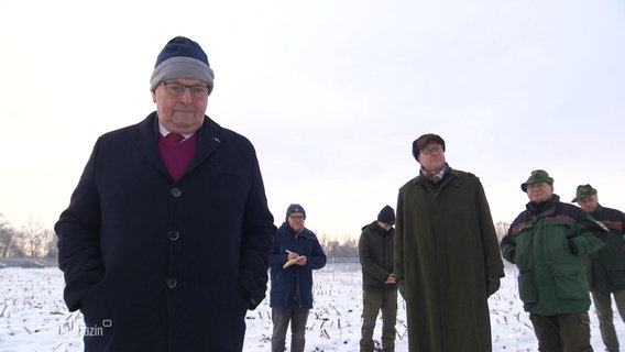 Eine Gruppe älterer Herren um Umweltminister Till Backhaus (SPD) schaut missmutig in den Wald. © Screenshot 