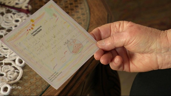 Eine ältere Person hält eine Weihnachtskarte in der Hand. © Screenshot 