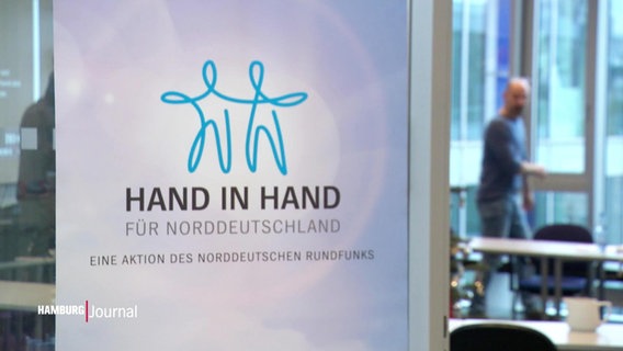 Auf einem Schild steht "Hand in Hand". © Screenshot 