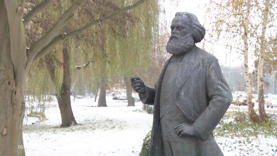 Die Karl-Marx-Statue vor winterlicher Kulisse. © Screenshot 