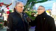 Landwirt Cort Meyer im Gespräch mit Reporter Olaf Kretschmer vor weihnachtlich geschmückten Traktoren. © Screenshot 