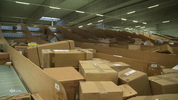 In einem Logistikzentrum liegen viele Pakete in einem Fließbandsystem. © Screenshot 