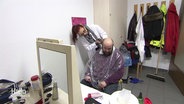 Eine Frau schneidet einem Mann mit Vollbart die Haare. © Screenshot 