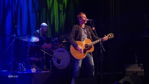 Michy Reincke in blauem licht bei einer Performance an der Gitarre © Screenshot 