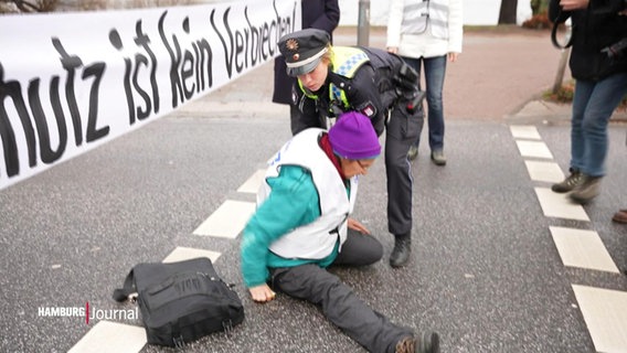 Eine Aktivistin wird von der Polizei von der Strasse gezogen © Screenshot 