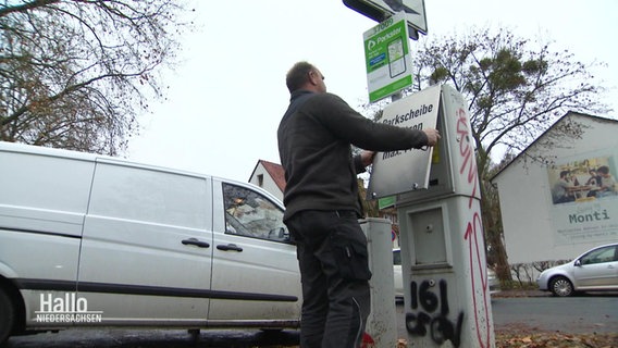 Ein Mann versiegelt einen Parkscheinautomat. © Screenshot 