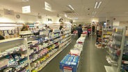 Blick in einen Gang in einer niederländischen Drogerie in dem die Warenregale mit Medikamenten gefüllt sind. © Screenshot 