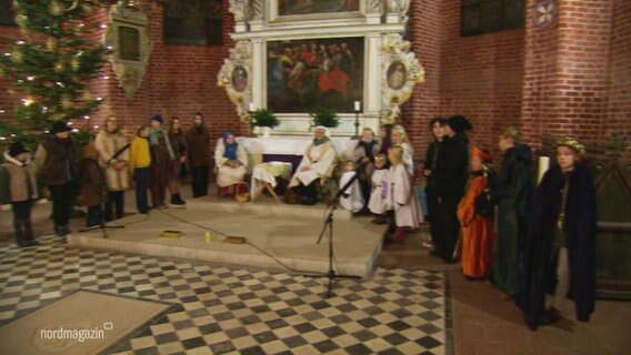 Kinderdarstellende haben sich vor dem Altar einer Kirch in Kostümen zu einem Krippenspiel aufgestellt. © Screenshot 