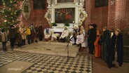 Kinderdarstellende haben sich vor dem Altar einer Kirch in Kostümen zu einem Krippenspiel aufgestellt. © Screenshot 