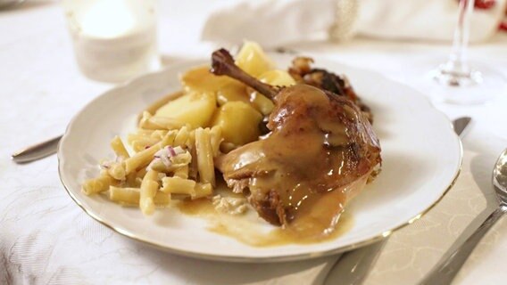 Auf einem Teller ist gebratene Ente mit Bohnensalat und Kartoffeln serviert. © Screenshot 