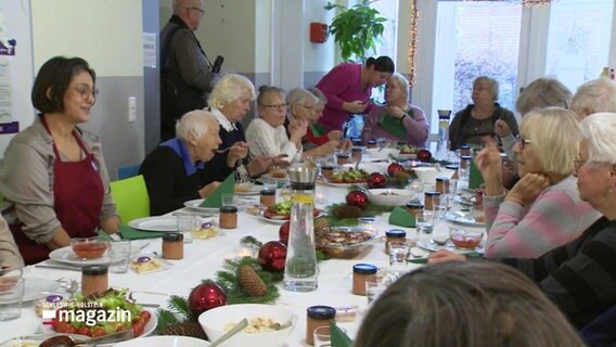 Mehrere Menschen sitzen zusammen an einem gedeckten Tisch und essen © Screenshot 