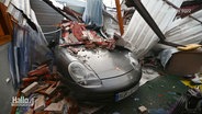 Ein Sportwagen ist unter Bauschutt und Ziegelsteinen einer eingestürzten Garage begraben. © Screenshot 