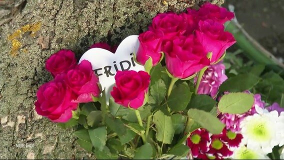 Ein Herz mit dem Namen Fridi lukt zwischen Rosen hervor, die an einer Gedenkstätte für eine Verkehrstote niedergelegt wurden. © Screenshot 