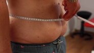 Der Bauchumfang eines Mannes wird mit einem Maßband gemessen. © Screenshot 