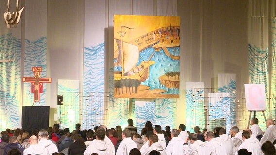 Beim Taizé-Treffen in Rostock sind viele hundert Menschen in einer Halle © Screenshot 