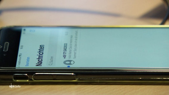 Auf einem Tisch liegt ein Handy auf dem eine neue Messenger-Nachricht angezeigt wird. © Screenshot 