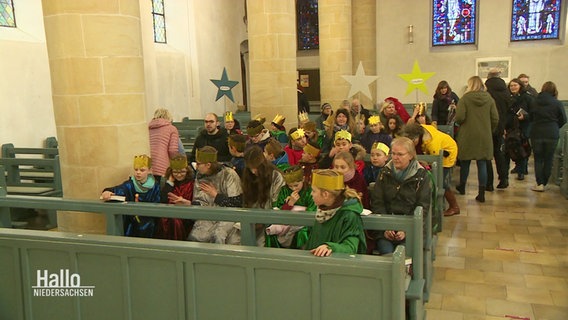 In einem Kirchenschiff sitzen viele als Sternensänger verkleidete Kinder auf den Kirchenbänken. © Screenshot 