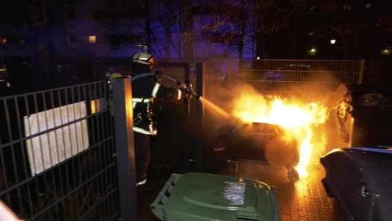 Ein Feuerwehrmann löscht eine brennende Mülltonne © Screenshot 
