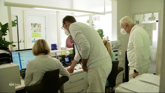 Mitarbeitende einer Arztpraxis hinter dem Empfangs-Tresen. © Screenshot 