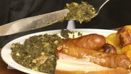 Auf einem Teller ist Grünkohl mit Wurst und Kartoffeln serviert. © Screenshot 
