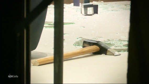 Blick aus der Ferne auf den Boden eines Pfandleihhauses auf dem zwischen Glasscherben eine Axt liegt. © Screenshot 