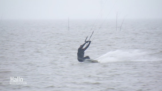 Ein Kite-Surfer surft im Wasser bei nebligem Wetter. © Screenshot 