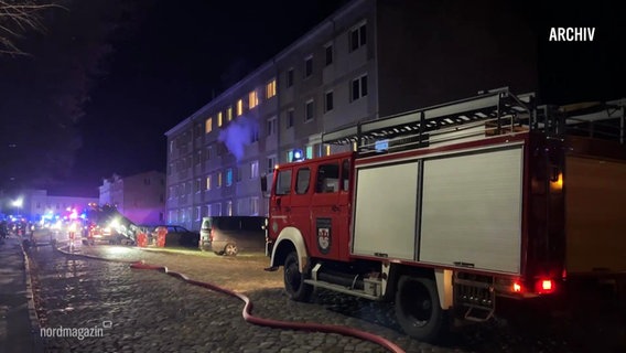 Ein Feuerwehrauto steht vor einem brennenden Wohnhaus. © Screenshot 