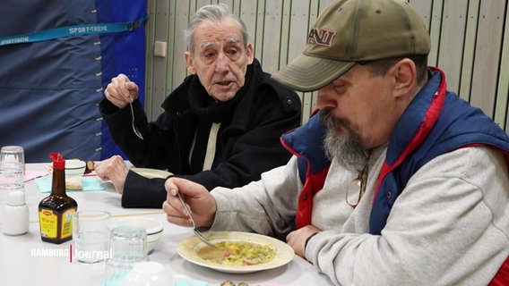 Zwei Männer essen einen Teller Suppe. © Screenshot 
