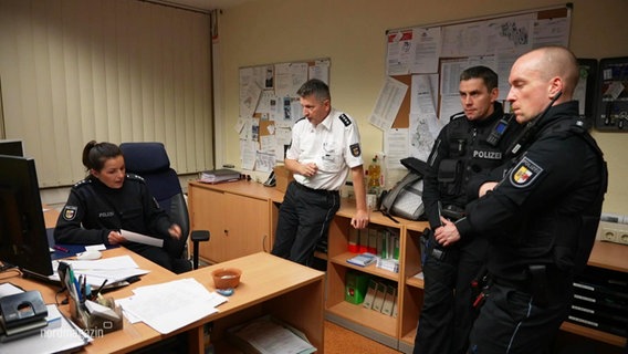 Drei Polizisten und eine Polizistin in Uniform in einem Büro. © Screenshot 